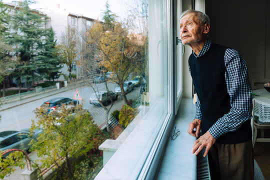 Senior man looking outside window