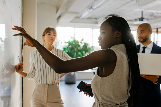 Business team brainstorming ideas on whiteboard in office