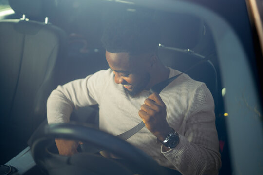 Man enjoying a car ride while fastening his seatbelt and smiling