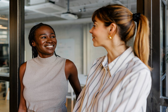 Businesswomen smiling and talking together in workplace