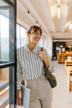 Professional woman leaving office building with laptop