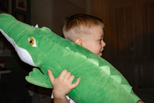 Child laughing while hugging a large green toy