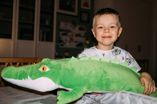 Child smiles with large green crocodile toy