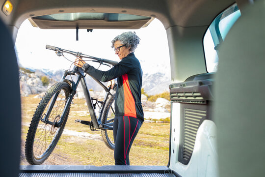 Woman loading mountain bike into the back of car