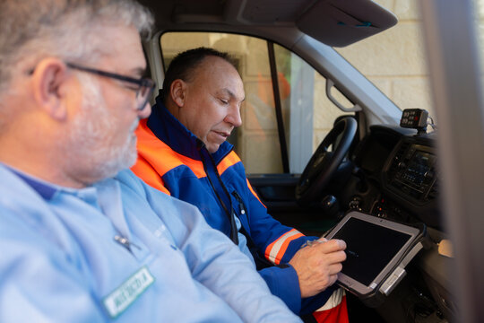 Emergency medical technicians using tablet inside ambulance