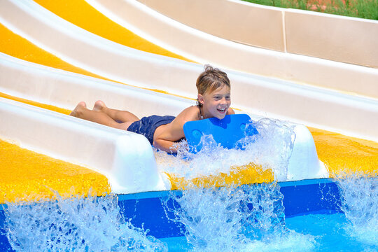 Boy sliding down water park water slide having fun