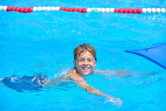 Happy boy swimming in clear blue pool water