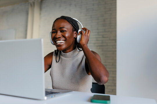 Woman with headphones working on laptop at office