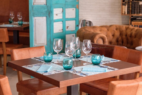 Restaurant table set with turquoise glasses and leather chairs