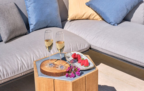 Champagne flutes and strawberries on outdoor patio furniture