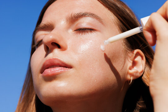 Skincare Woman Applies Moisturizing Cream  Blue Sky background