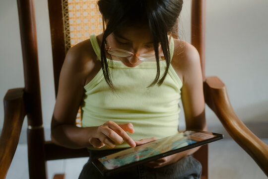 Child learning with digital tablet in rocking chair