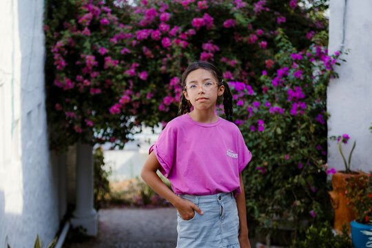 Young girl wearing glasses standing in a flowery garden