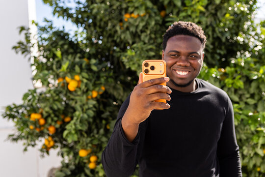 Smiling Man Taking a Selfie in Front of Orange Tree