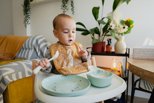 Baby toddler learning eating with spoon at mealtime