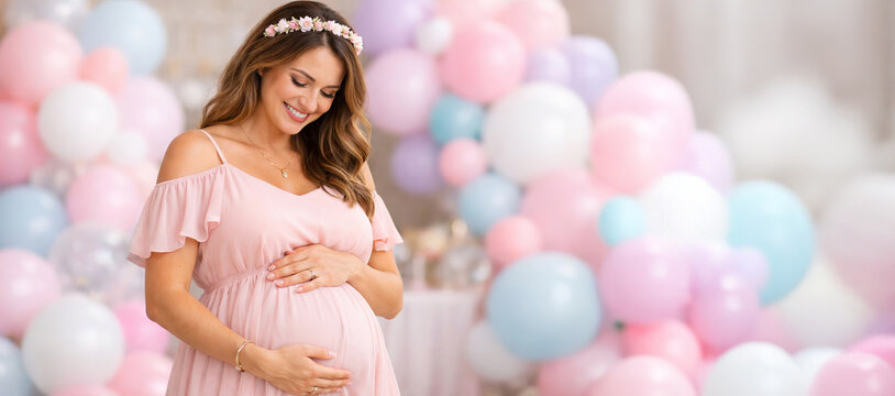 Joyful expectant mother at baby shower celebration surrounded by festive pastel balloons indoors. concept of motherhood, anticipation, event celebration, copy space, banner