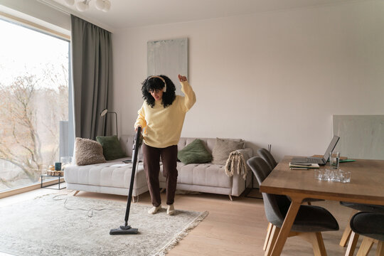 Woman vacuuming and dancing in modern living space