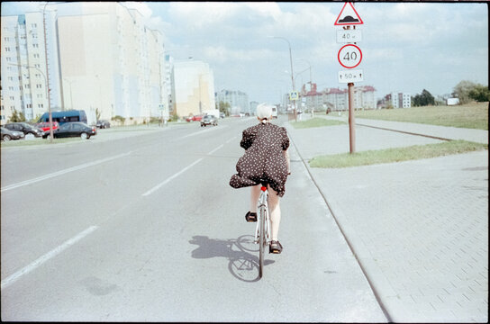 A young woman in a black dress is cycling.