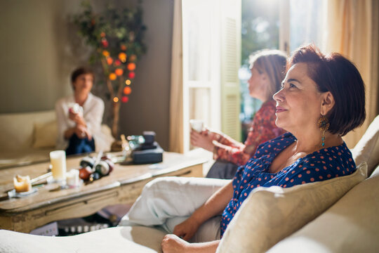 Thoughtful middle-aged woman relaxing with friends at home