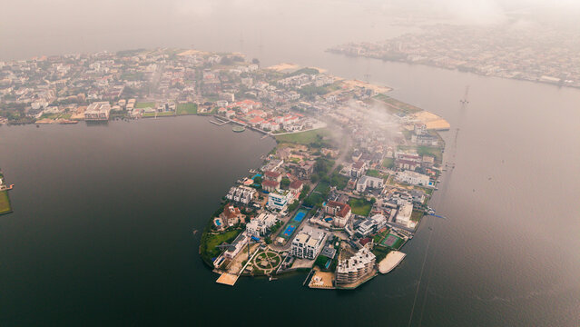 Aerial view of the upscale Banana Island's opulent residences nestled in Lagos Lagoon, a symphony of architectural styles reflecting in the calm water, Lagos, Nigeria.