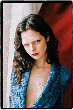 Woman in blue lace suit near curtain light