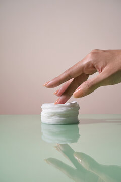 Hand gently touching a stack of soft cotton pads