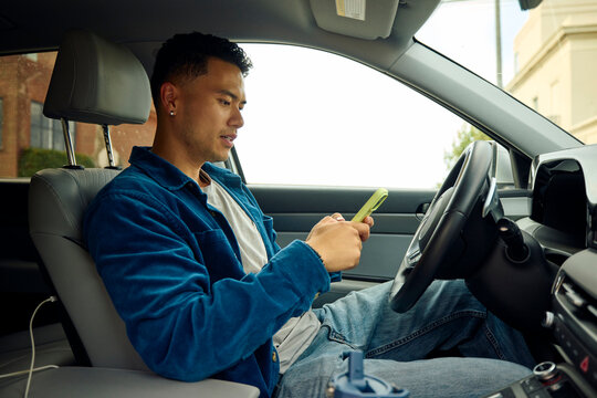 Handsome man is using his phone in a car