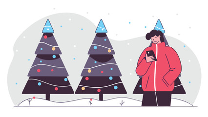 Person in a red jacket looking at a phone while standing near festive Christmas trees covered in snow.