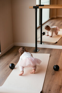 Baby girl crawling on yoga mat in ballet studio