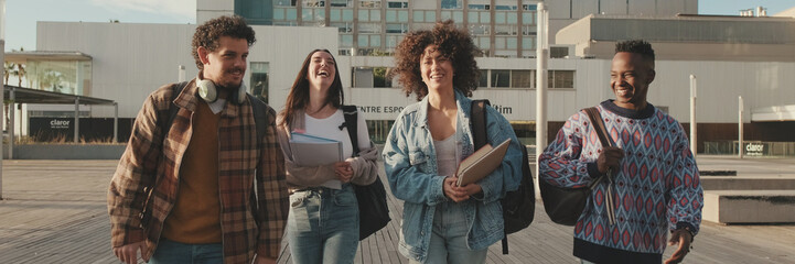 Group of students are walking from outside. Classmates students walk down the street talking and laughing together. Panoramic