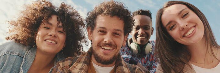 Happy smiling friends make a video call from a mobile phone. Four students wave their hands in...