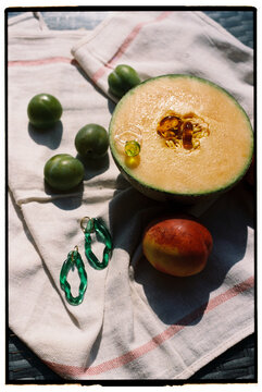 A still life with fruits melon, peach, and plums &mdash; with an accessory