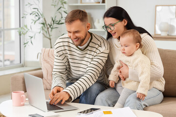 Young couple with their baby and laptop planning budget at home