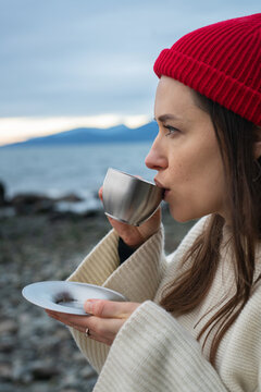 Young female drinking from a small metal cup on a BC beach.