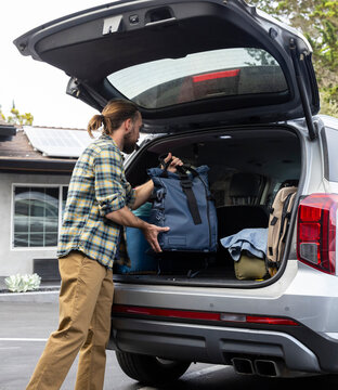 Road Trip man put luggage in trunk of car 