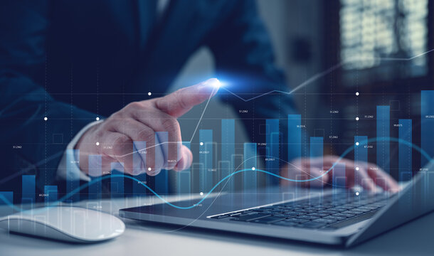 Businessman analyzing financial dashboard with glowing growth charts on laptop. Concept of digital data analysis, stock market investment strategy, business success with futuristic virtual interface.