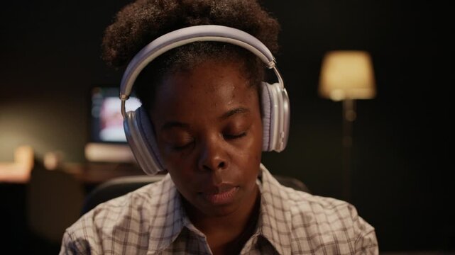 Tilt shot of African American retoucher with headphones using interactive tablet to edit images while working in studio
