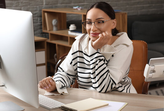 Beautiful young female programmer working with computer in modern office