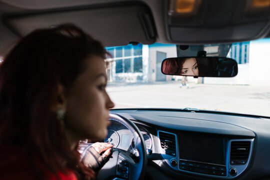 Woman driving car looking in rearview mirror