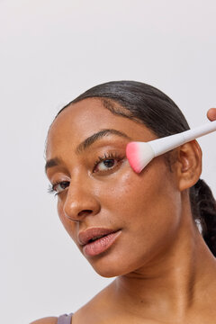 Woman using a face brush in studio 