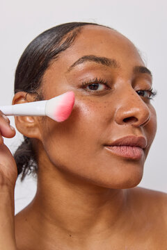 Woman using a face brush in studio 