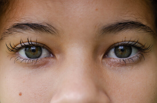 Hazel eyes are catching rectangular light lashes and brows framing nose bridge and mole near window