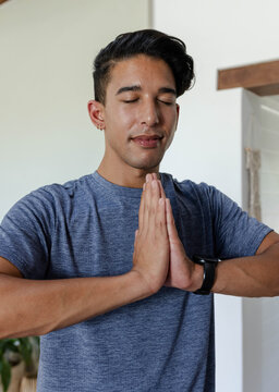 African American man standing at home, pressing palms together, wearing gray T-shirt and smartwatch