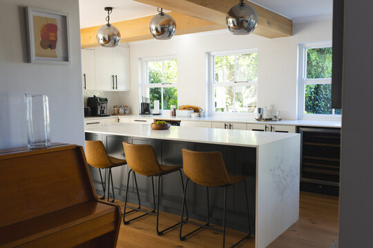 Kitchen island showing white waterfall countertop dark-gray base with stools in open-plan kitchen