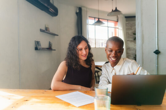 Women smile and help each other at work