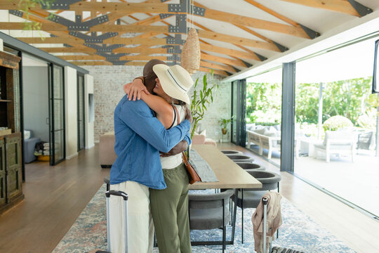 Long wooden dining table is running through open-plan area, suitcases are waiting by sliding doors