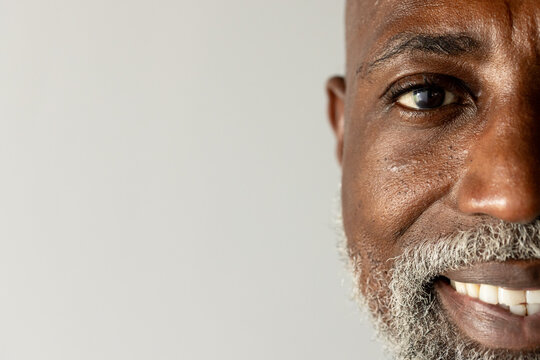Mature African man smiling at studio backdrop, showing teeth and salt-and-pepper beard, copy space