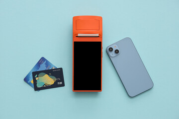 Fototapeta premium Payment terminal with credit cards and mobile phone on blue background