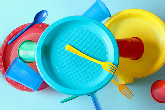 Colorful plastic tableware levitating on blue background