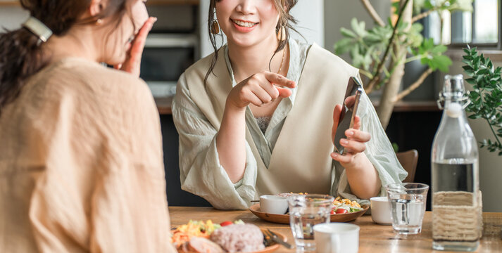 Cafe, coffee shop, woman talking while looking at smartphone at dining table